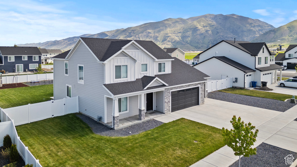 View of front facade with concrete driveway, board and batten siding, a mountain view, a residential view, and covered porch