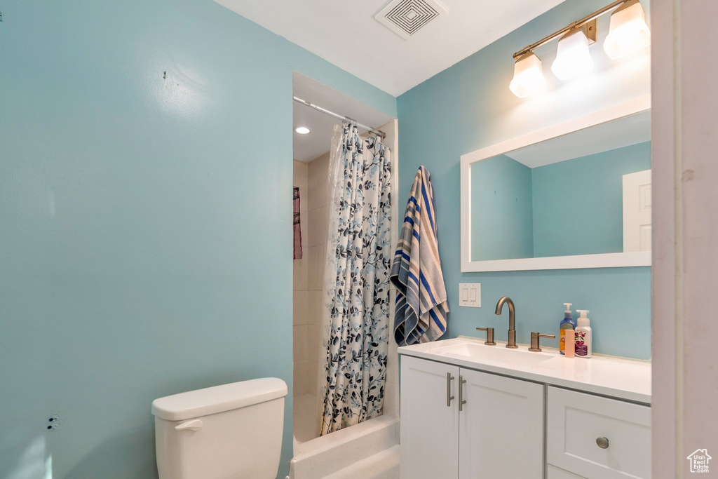 Full bath with a shower with shower curtain, visible vents, toilet, and vanity