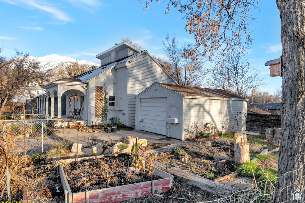 Rear view of property with fence, a shed, a vegetable garden, an outdoor structure, and a mountain view