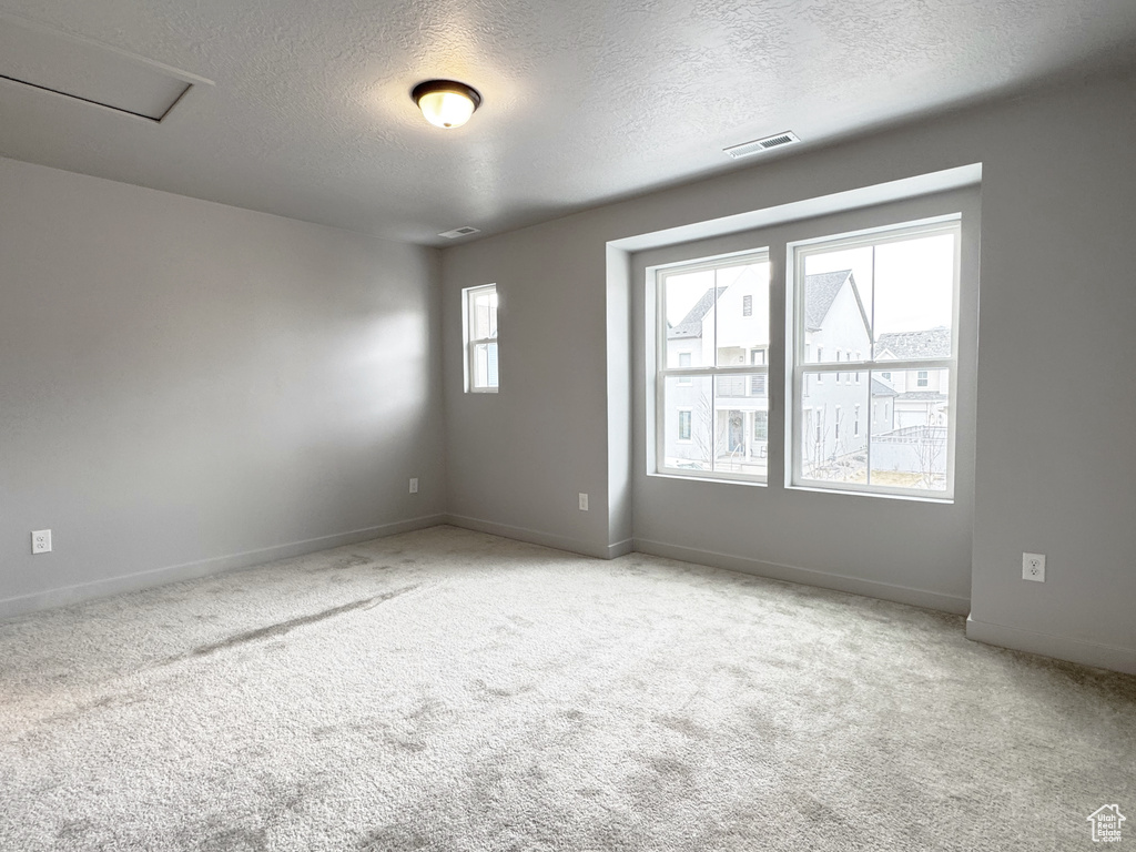 Carpeted spare room with visible vents, baseboards, and a textured ceiling