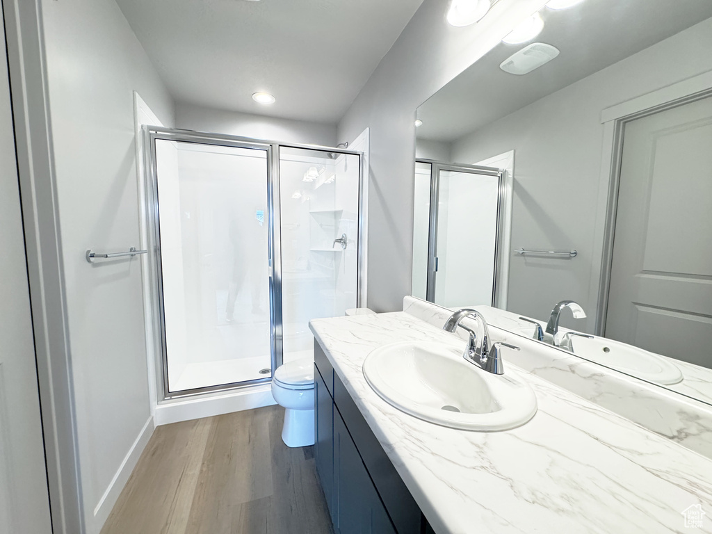 Full bath with vanity, toilet, wood finished floors, and a shower stall