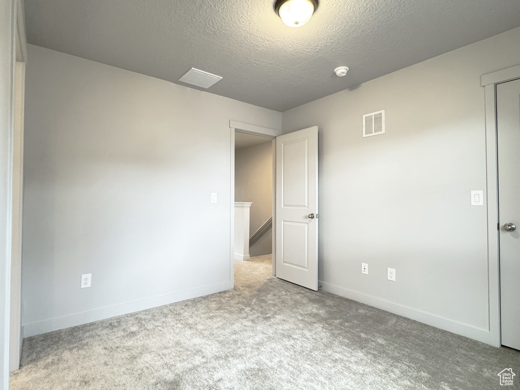 Spare room featuring baseboards, visible vents, a textured ceiling, and carpet