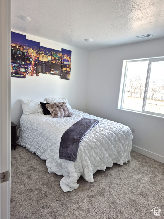 Bedroom featuring visible vents, baseboards, a textured ceiling, and carpet flooring