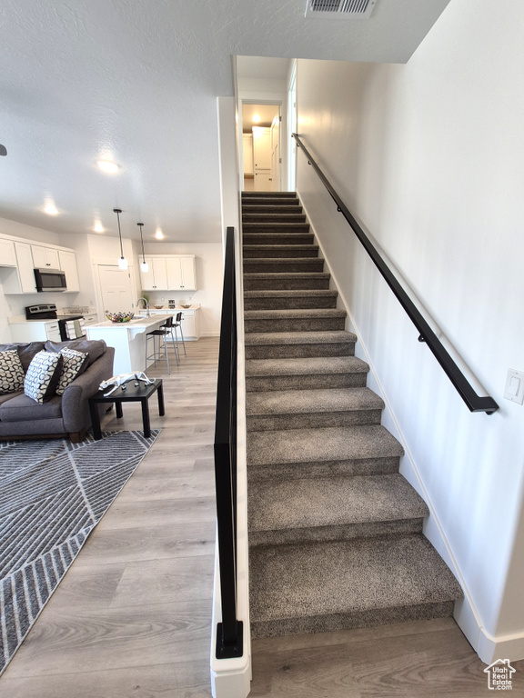 Staircase with wood finished floors, visible vents, and baseboards