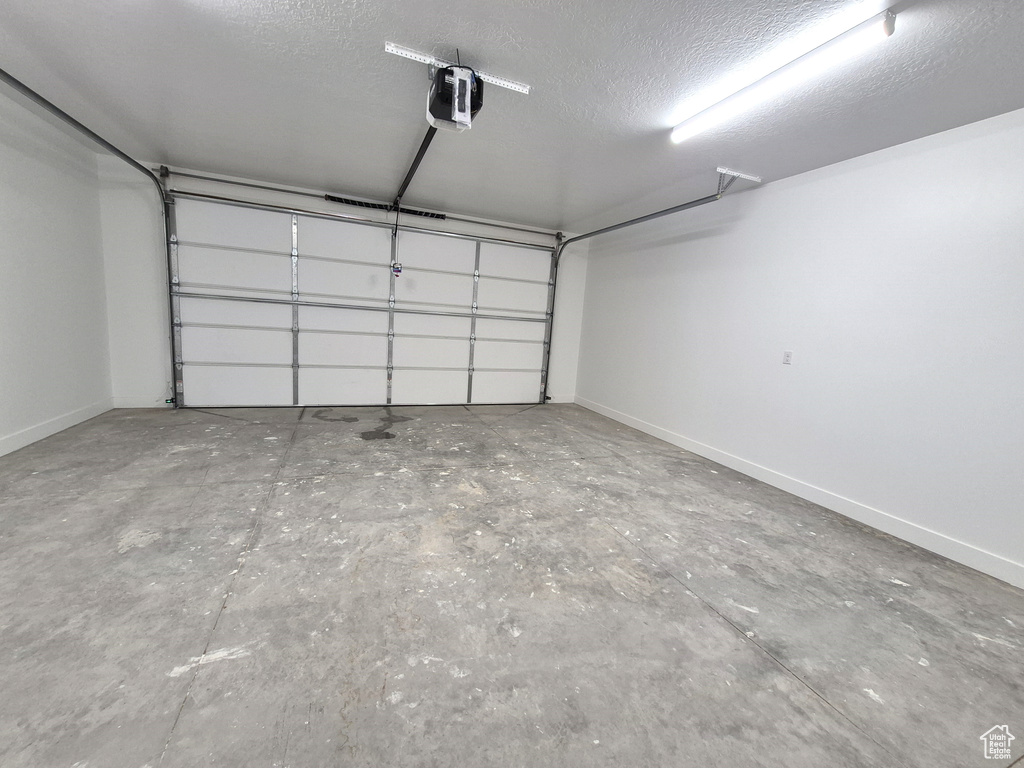 Garage featuring a garage door opener and baseboards