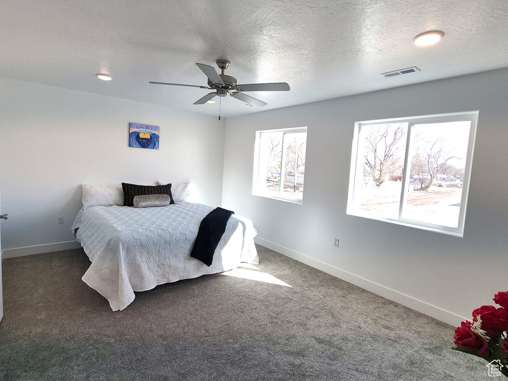 Carpeted bedroom with visible vents, a textured ceiling, and baseboards