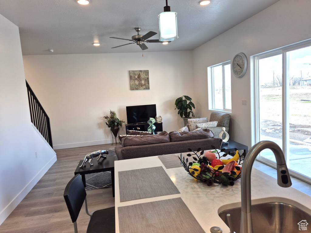 Living area with wood finished floors, recessed lighting, baseboards, ceiling fan, and stairs