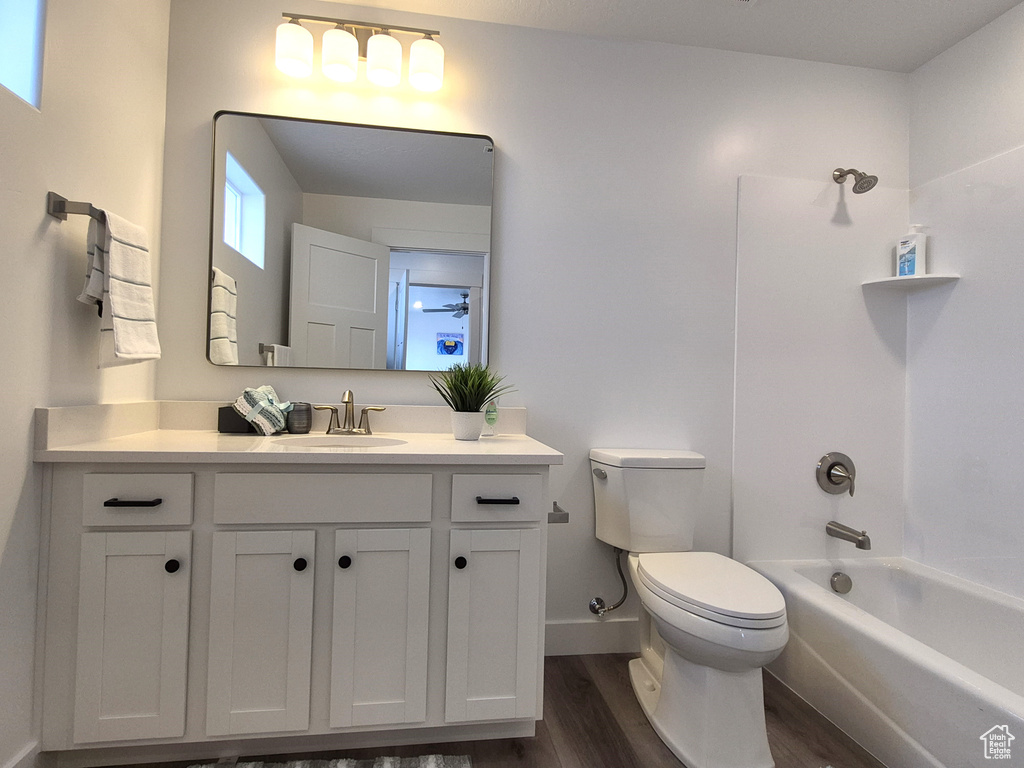 Full bathroom with baseboards, toilet, bathing tub / shower combination, wood finished floors, and vanity