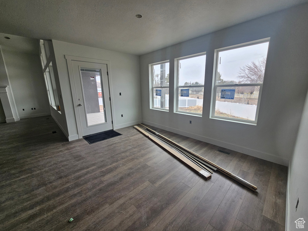 Entryway with dark wood-type flooring, visible vents, baseboards, and a textured ceiling