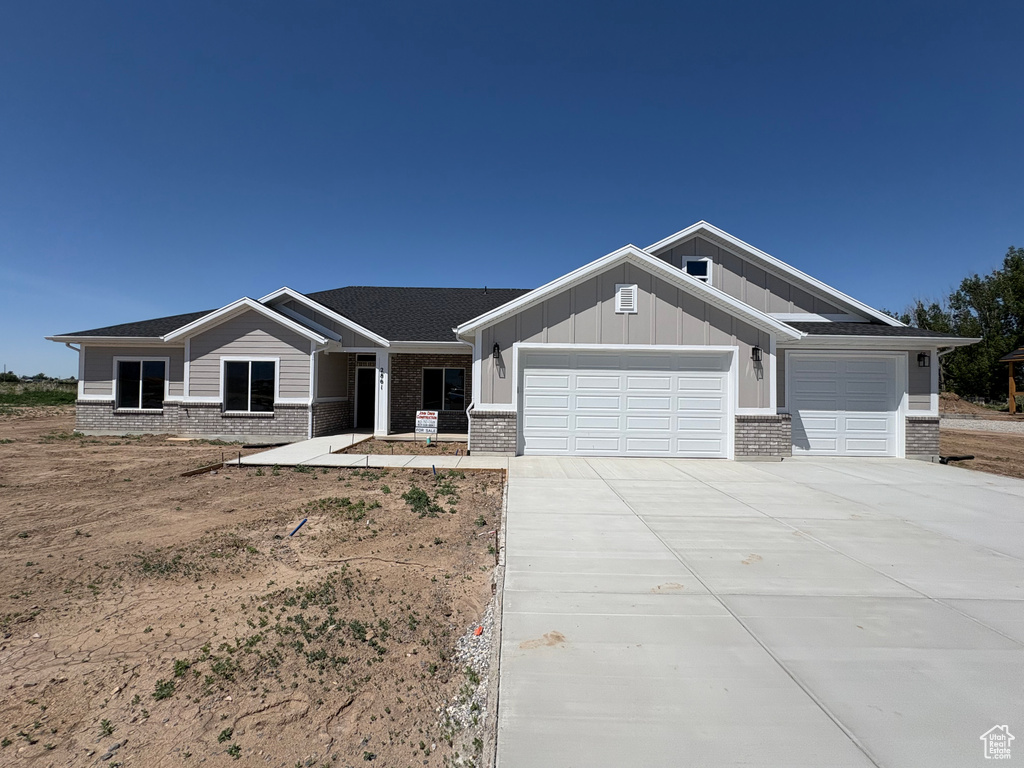 Craftsman inspired home featuring brick siding, an attached garage, board and batten siding, and driveway