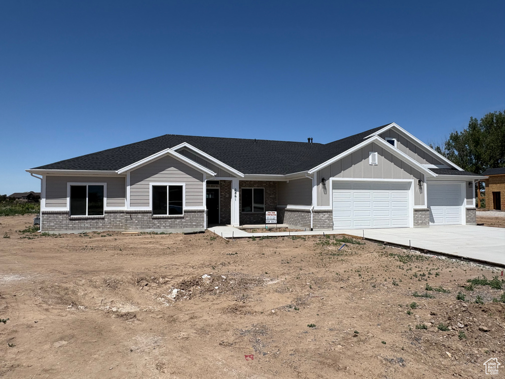 View of front facade featuring an attached garage, brick siding, driveway, board and batten siding, and covered porch