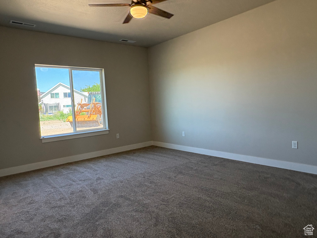 Carpeted empty room with a ceiling fan and baseboards