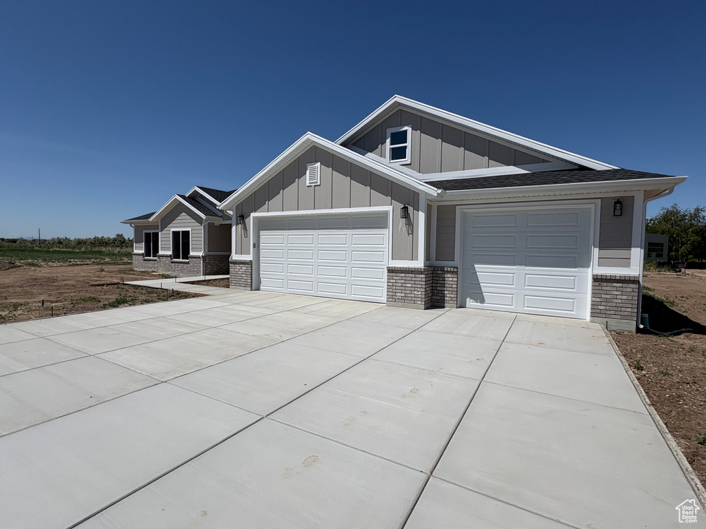 Craftsman-style house featuring brick siding, board and batten siding, concrete driveway, and a garage