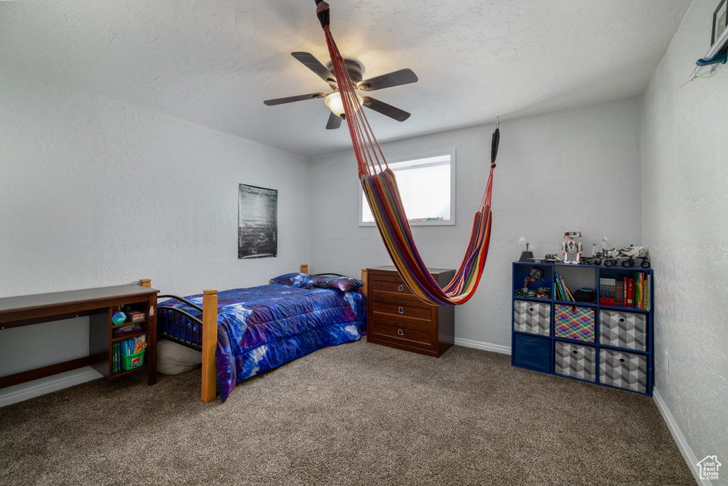 Bedroom with a ceiling fan, a textured wall, baseboards, and carpet floors