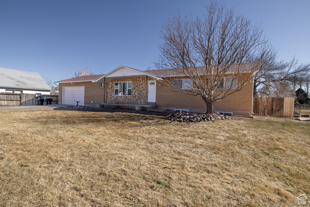 Ranch-style house featuring a garage, a front lawn, and fence