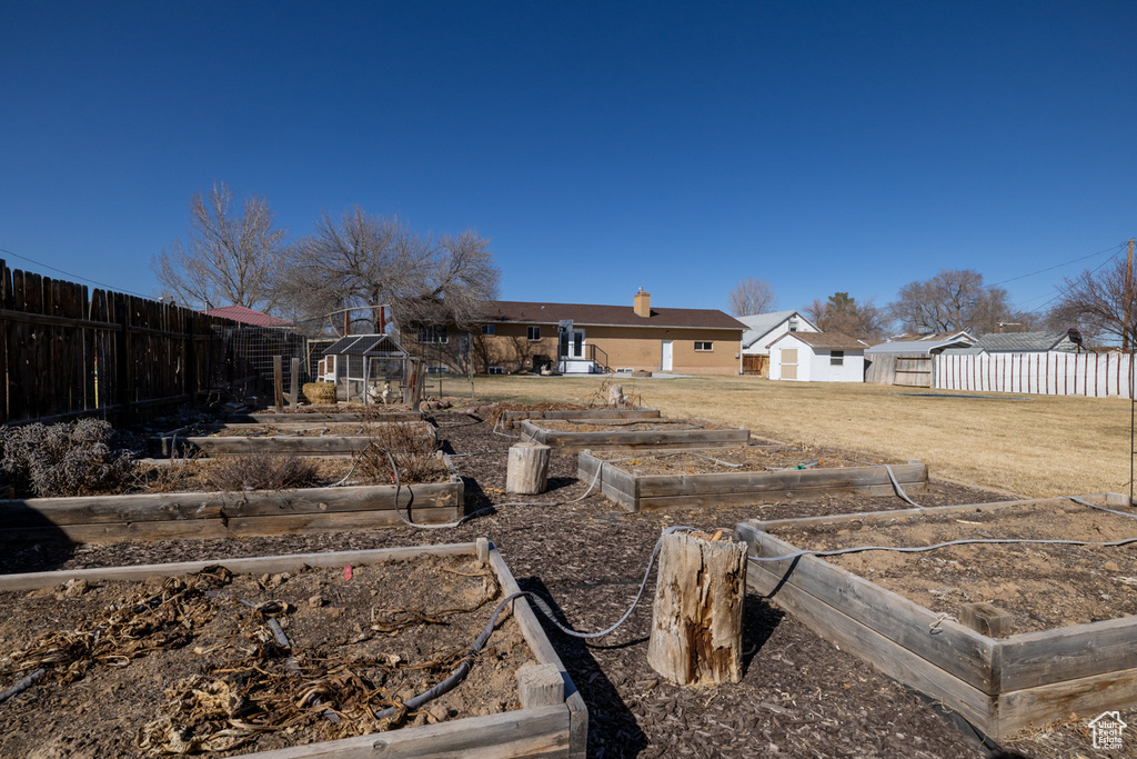 View of yard featuring a greenhouse, a vegetable garden, an outdoor structure, and fence