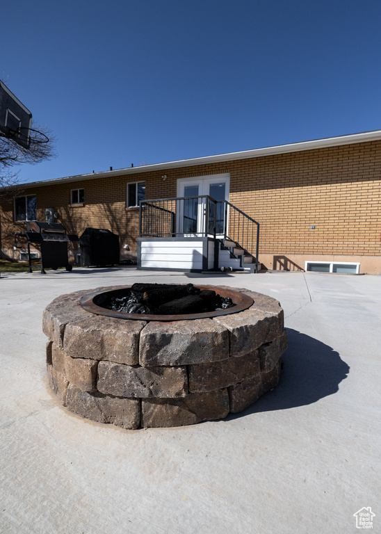 Back of house featuring brick siding and a fire pit