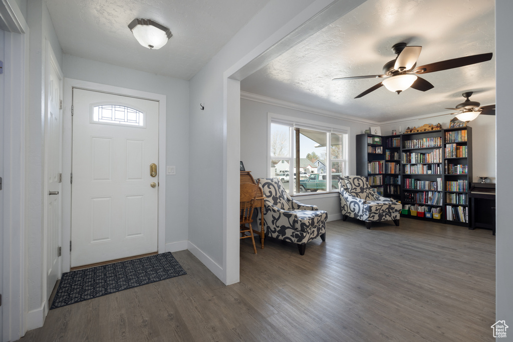 Entrance foyer featuring crown molding, baseboards, wood finished floors, a textured ceiling, and a ceiling fan