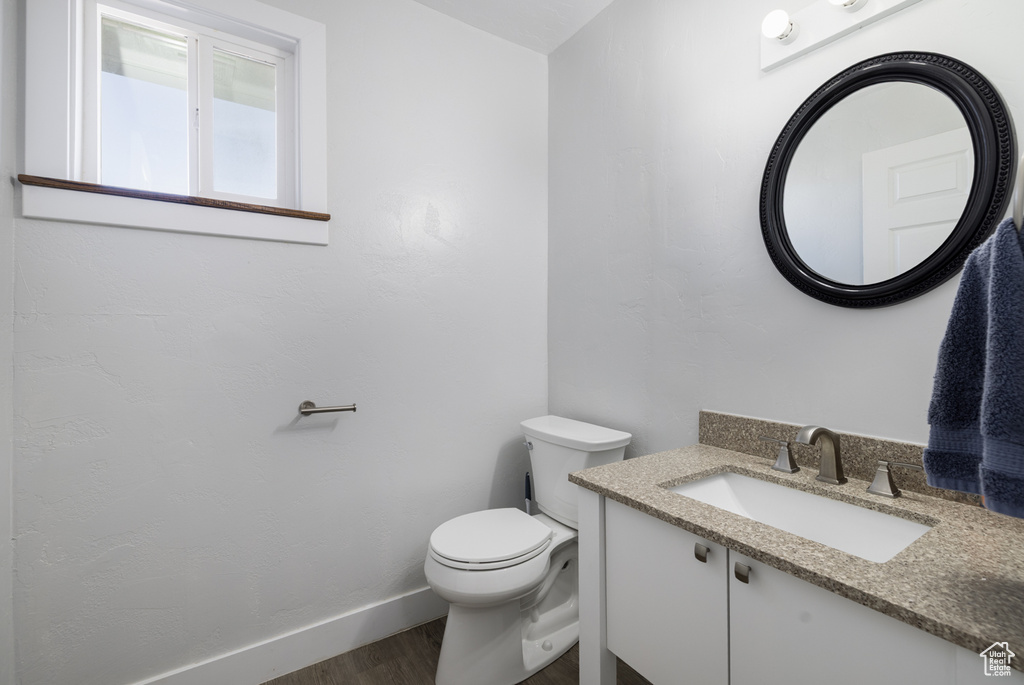 Bathroom with toilet, vanity, baseboards, and wood finished floors