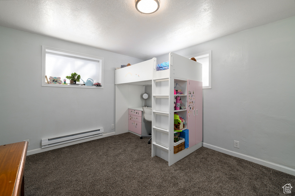 Bedroom with multiple windows, baseboard heating, carpet floors, and a textured ceiling