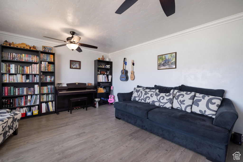 Living room with ornamental molding, a textured ceiling, a ceiling fan, and wood finished floors
