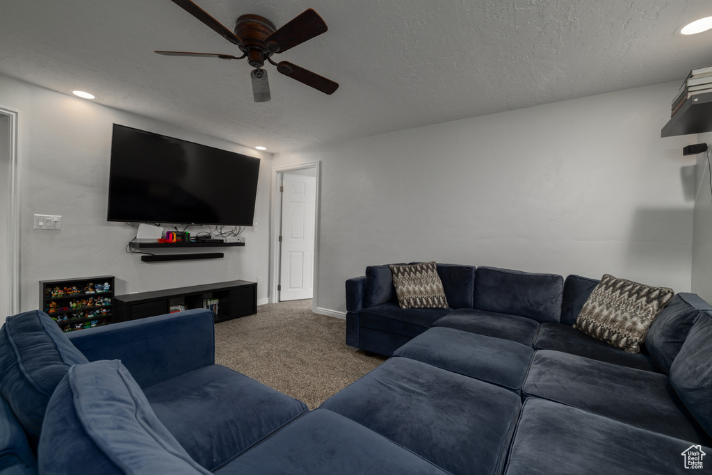 Carpeted living room featuring a ceiling fan, baseboards, and a textured ceiling