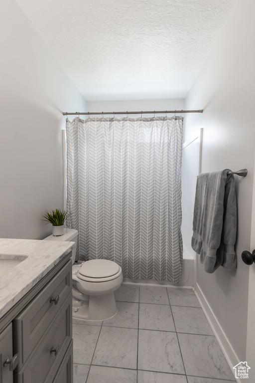 Full bath with vanity, baseboards, shower / bath combo with shower curtain, toilet, and marble finish floor