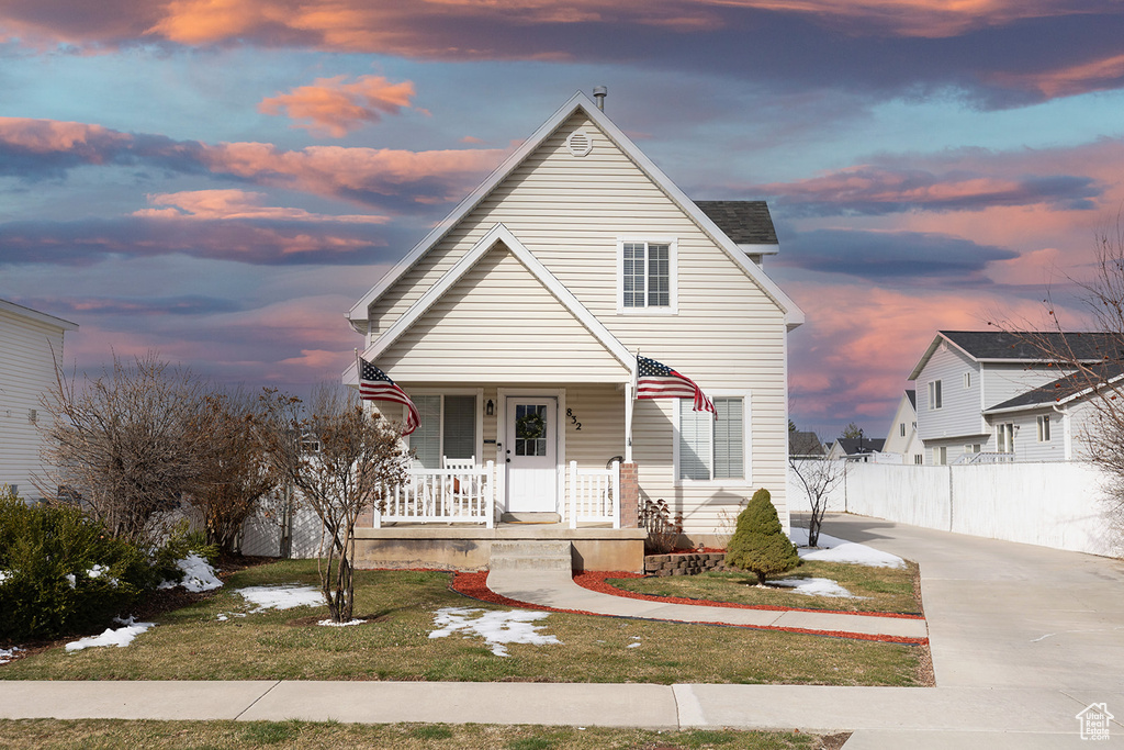 View of front of home with fence, covered porch, and a lawn