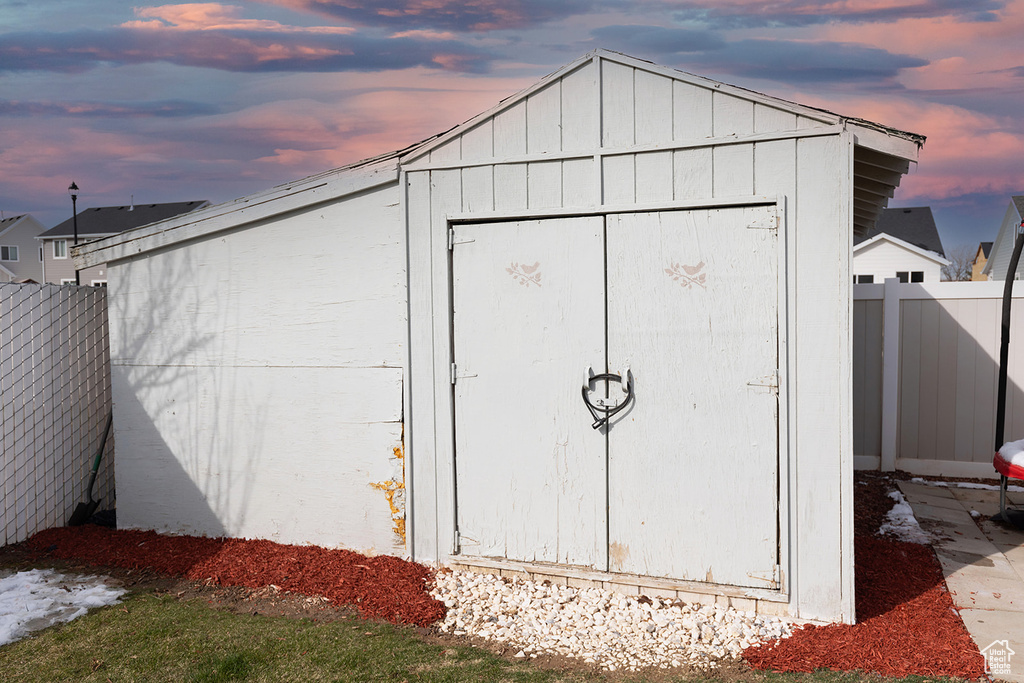 Outdoor structure at dusk with an outbuilding, a storage shed, and fence