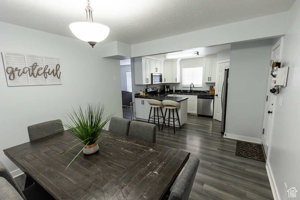 Dining area with a textured ceiling, dark wood-type flooring, and baseboards