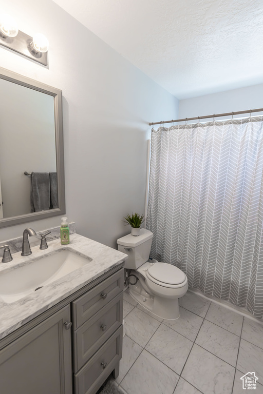 Full bath featuring marble finish floor, curtained shower, toilet, and vanity