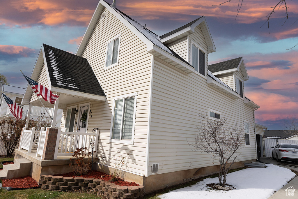 View of side of home featuring a porch and a shingled roof