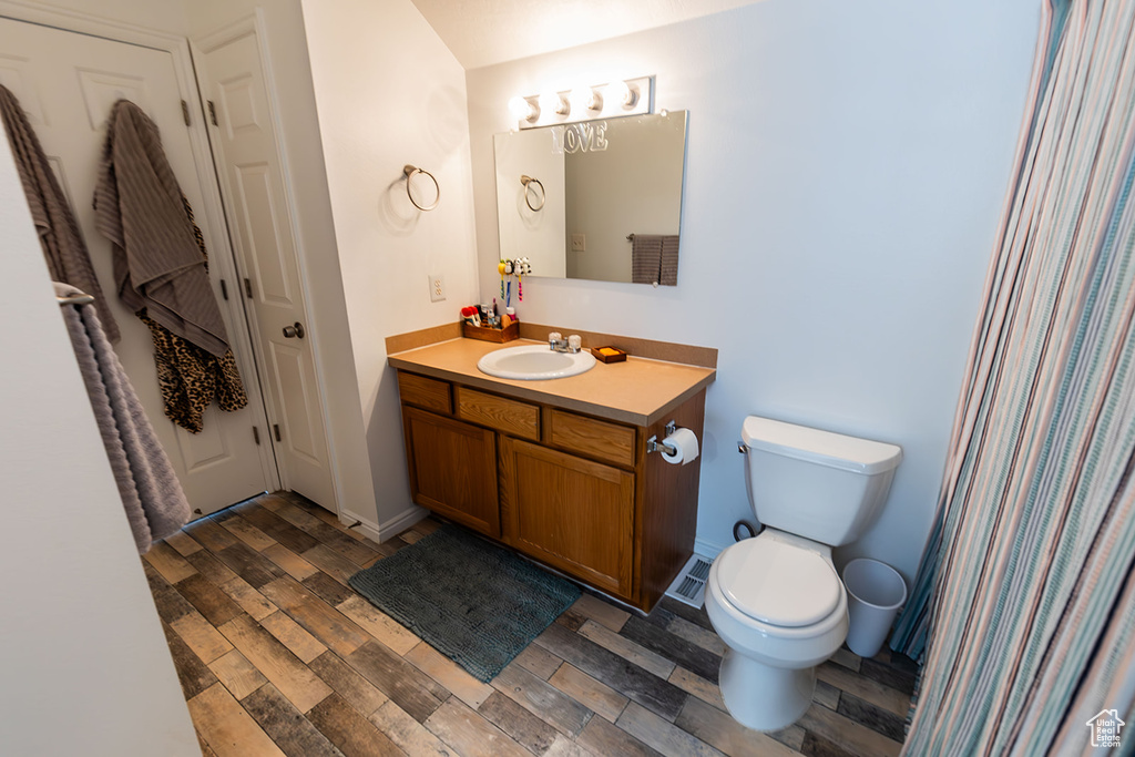 Bathroom featuring baseboards, toilet, wood finished floors, and vanity