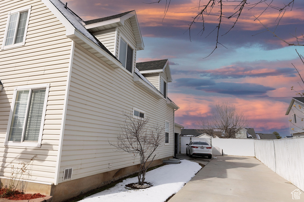 Property exterior at dusk with roof with shingles and fence