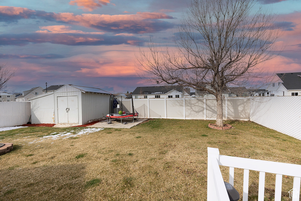 View of yard with an outbuilding, a fenced backyard, a storage unit, a trampoline, and a residential view
