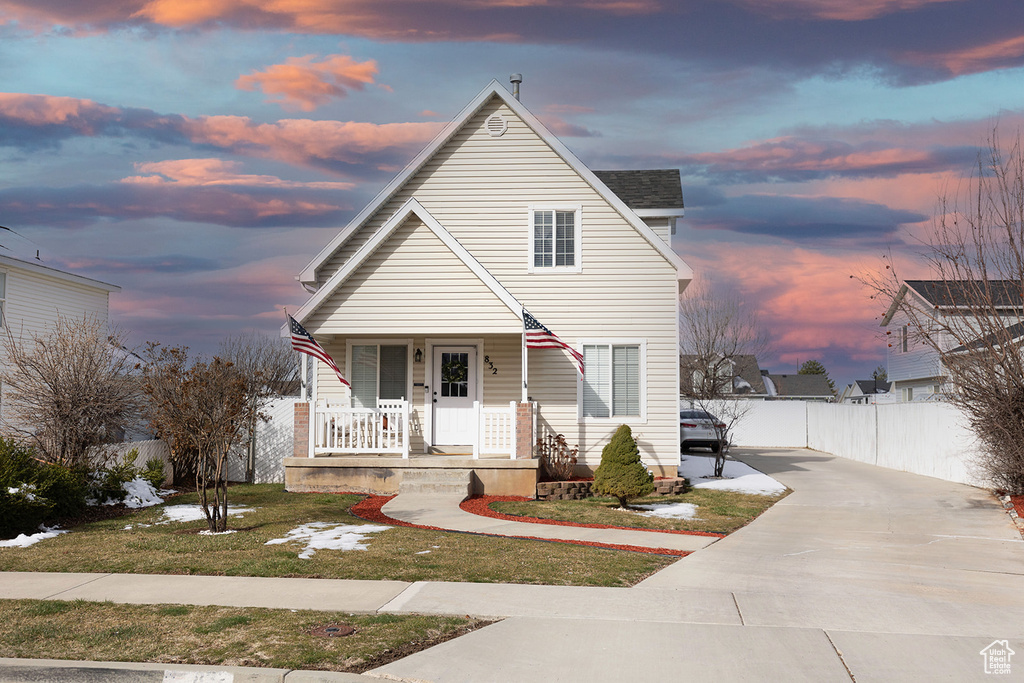 View of front of property with a lawn, a porch, driveway, and fence