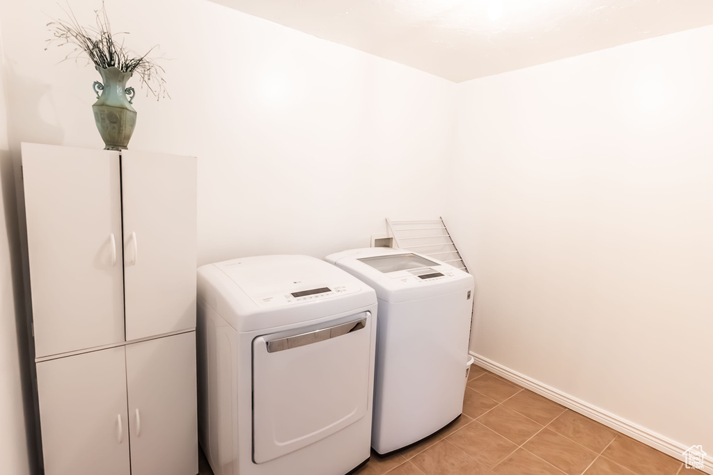 Laundry room with light tile patterned floors, cabinet space, independent washer and dryer, and baseboards