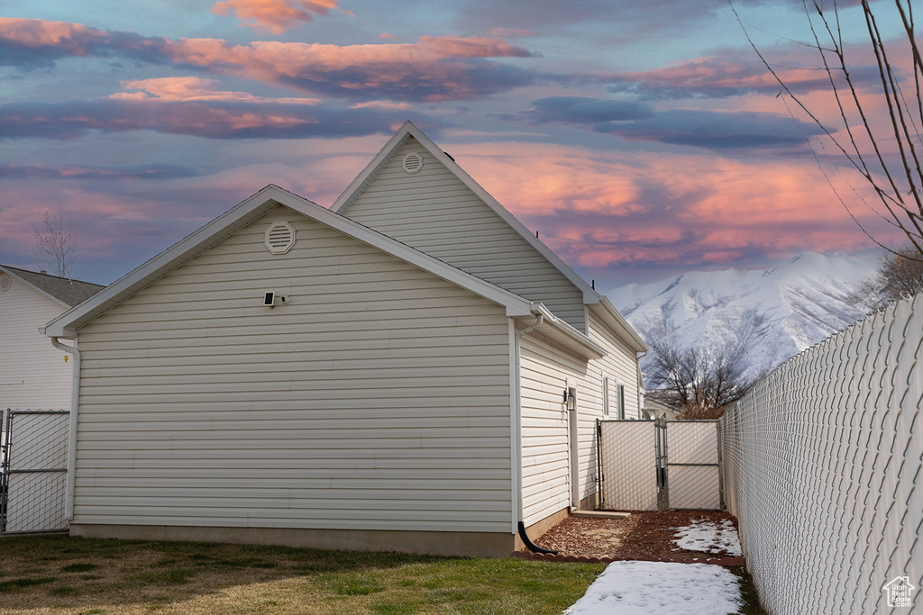 View of side of home featuring a mountain view, fence, and a gate