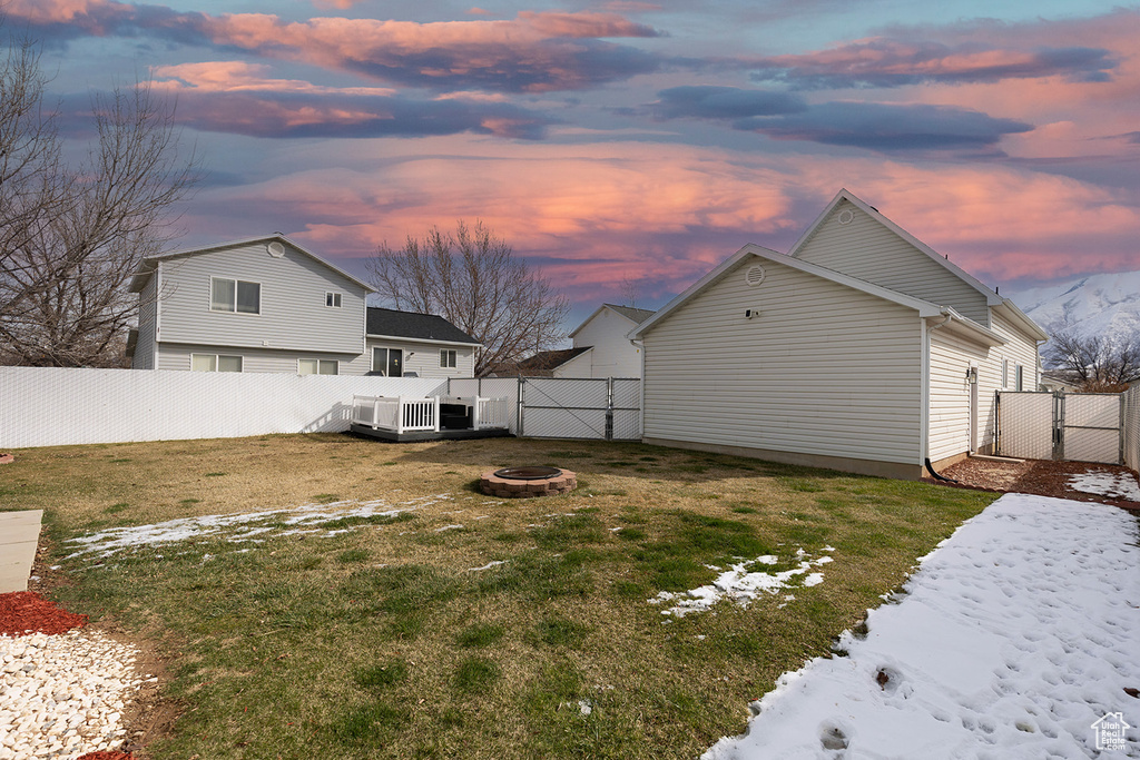 Yard at dusk featuring a gate, a fire pit, cooling unit, and a fenced backyard