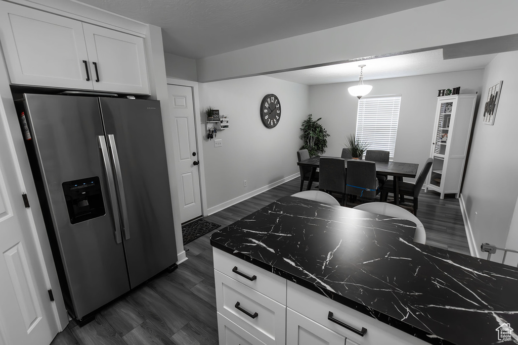 Kitchen featuring stainless steel fridge, dark countertops, white cabinets, and dark wood-style flooring