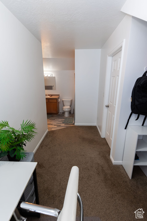 Hall with baseboards, a textured ceiling, and carpet flooring