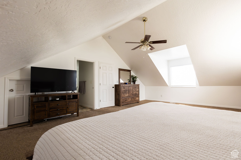 Bedroom featuring lofted ceiling, a textured ceiling, carpet flooring, baseboards, and ceiling fan