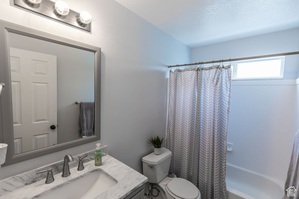 Full bathroom with shower / bathtub combination with curtain, toilet, and vanity