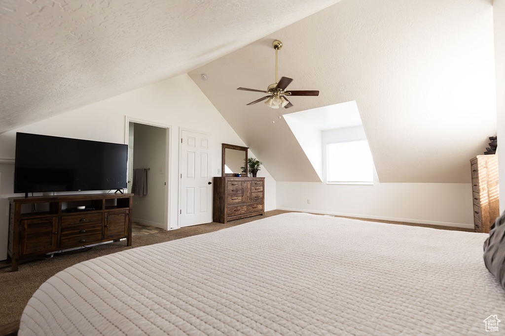 Bedroom featuring baseboards, ceiling fan, vaulted ceiling, a textured ceiling, and carpet flooring