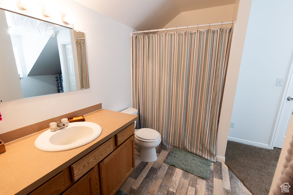 Full bathroom featuring toilet, vanity, lofted ceiling, and wood finished floors