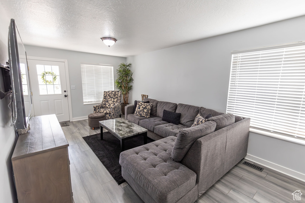 Living area with light wood-style flooring, baseboards, visible vents, and a textured ceiling
