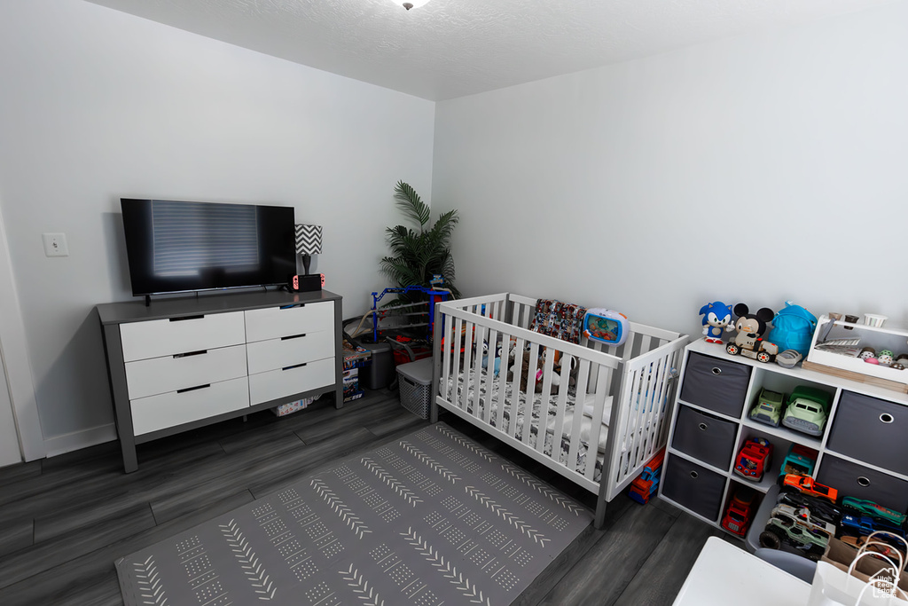Bedroom with baseboards, a nursery area, and wood finished floors