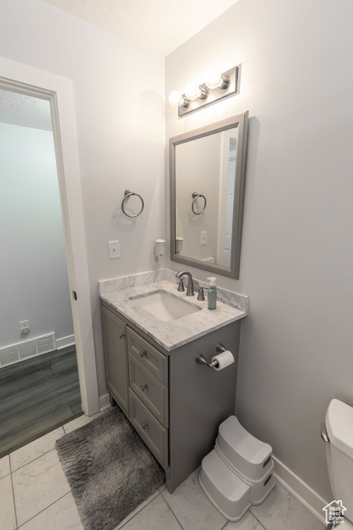 Bathroom featuring vanity, baseboards, visible vents, toilet, and marble finish floor