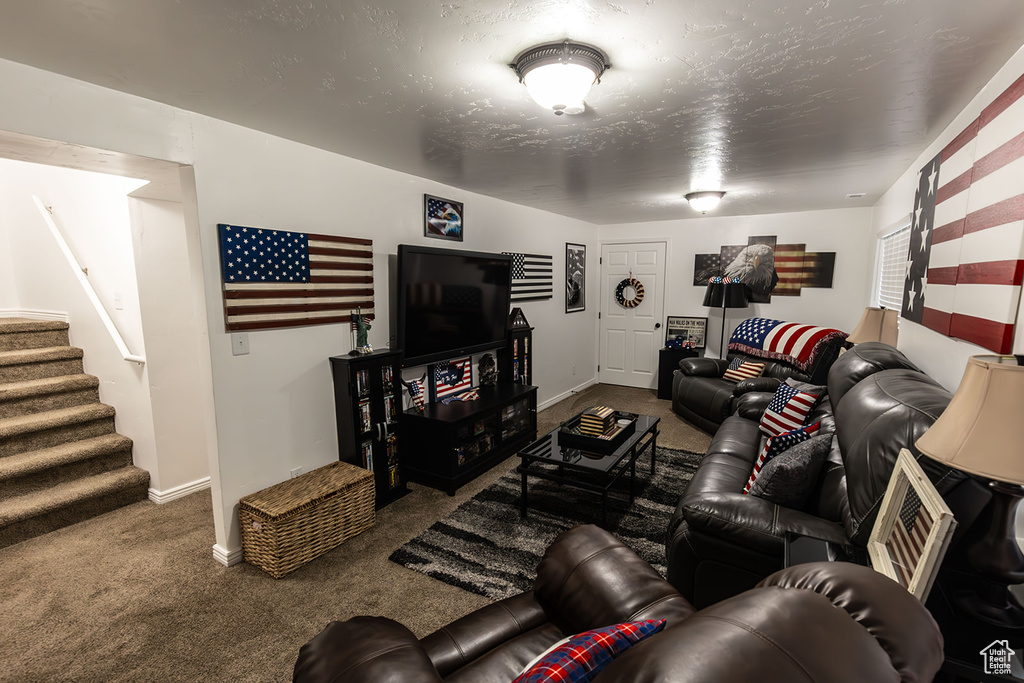 Carpeted living area featuring stairway, baseboards, and a textured ceiling