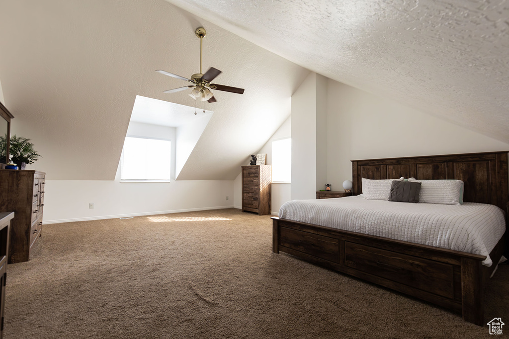 Bedroom featuring baseboards, a textured ceiling, vaulted ceiling, and carpet